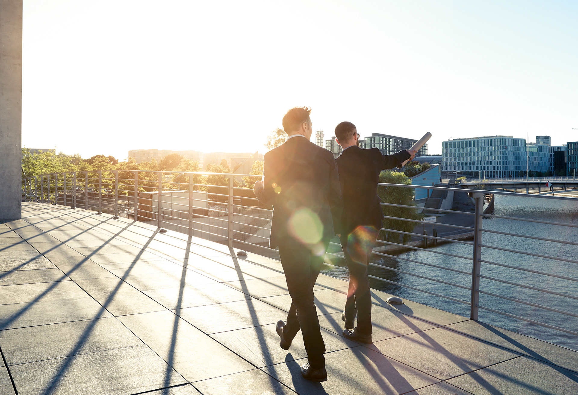 two men walking on bridge with sunset in background