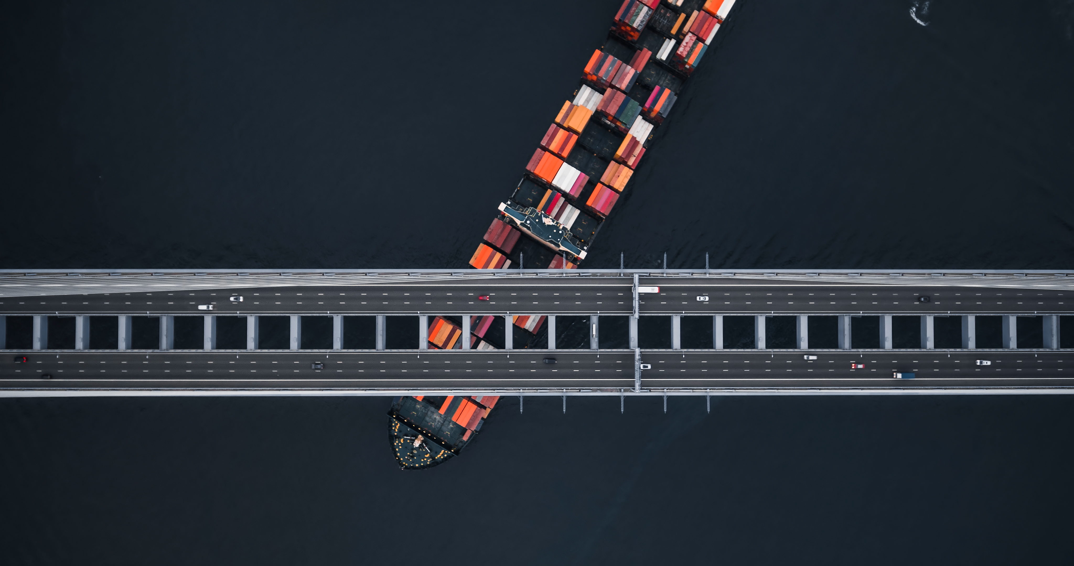 cargo vessel passing under bridge from overhear view