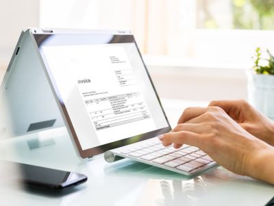 Un'impiegata nel suo ufficio compila una fattura al computer