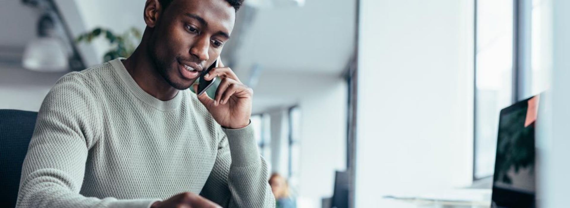 Un imprenditore seduto alla sua scrivania è al telefono con un cliente
