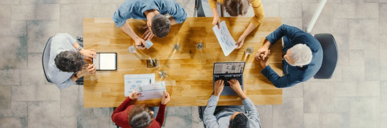 Sala riunioni di una startup team di imprenditori seduti attorno al tavolo conferenze mentre discutono