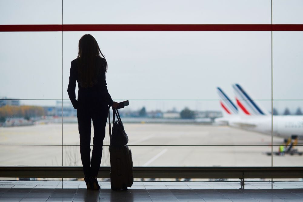 vrouw op vliegveld kijkend naar landingsbaan
