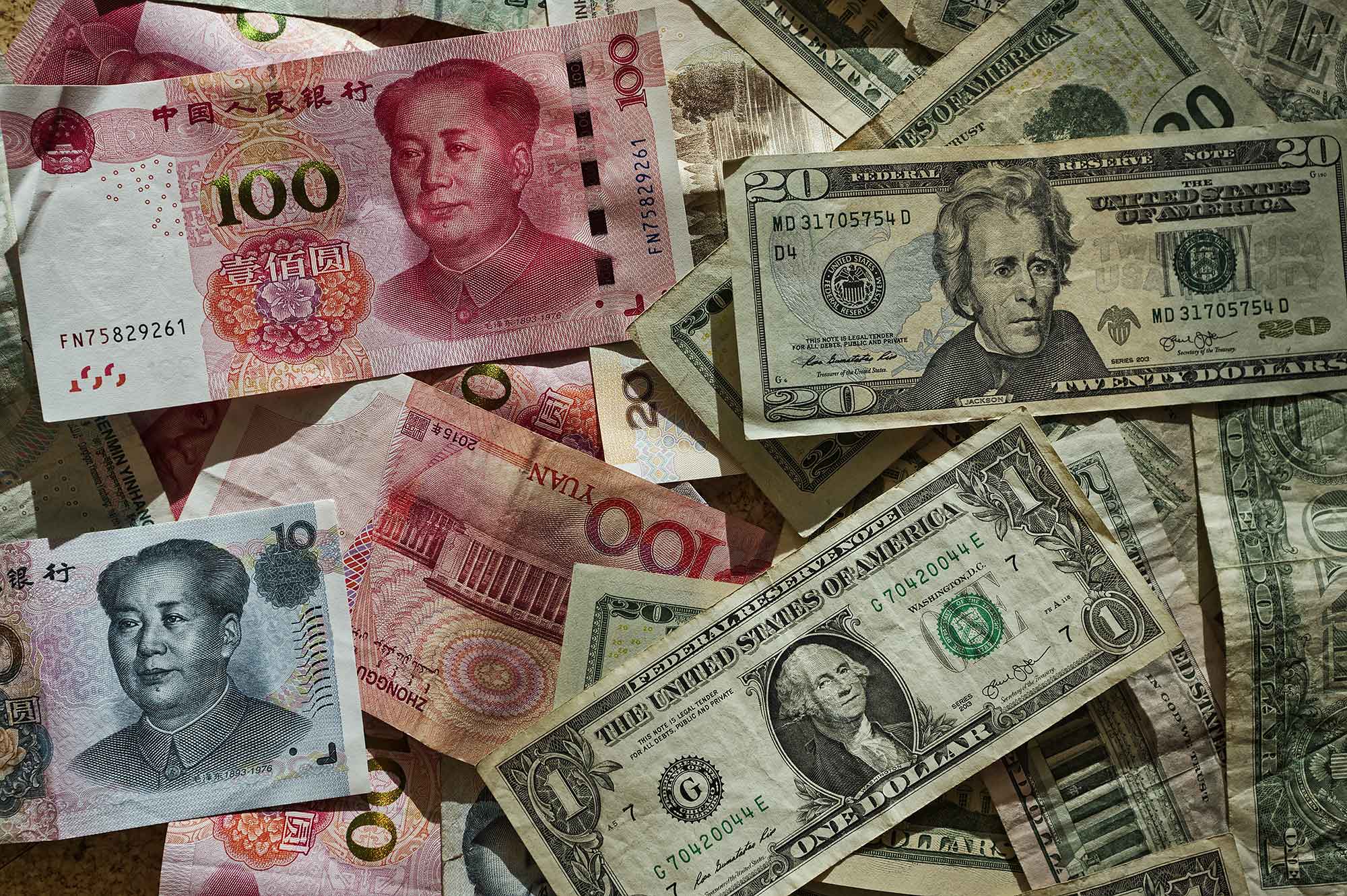 Banknoty dolarowe i juanowe rozrzucone na powierzchni