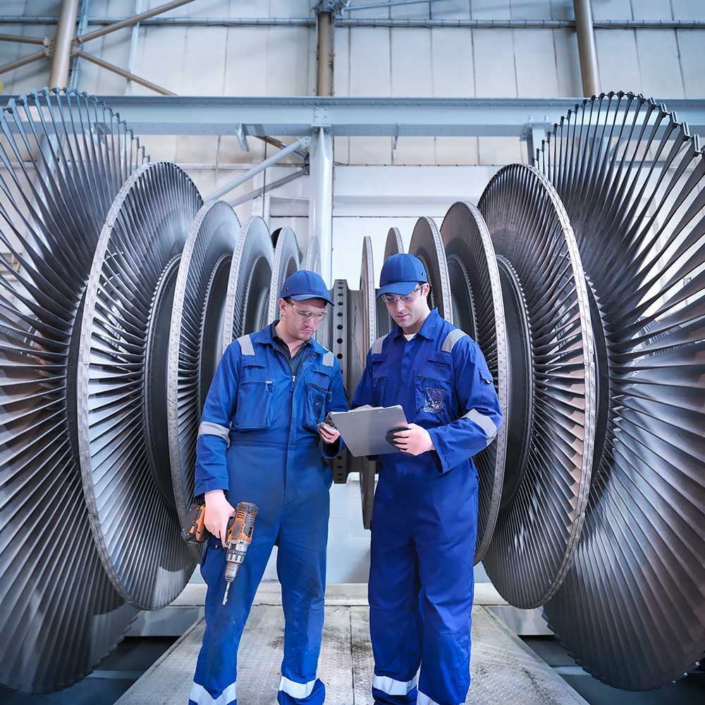 Dwóch pracowników na tle wielkich turbin