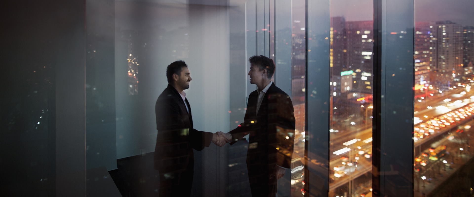 Δύο επιχειρηματίες δίνουν τα χέρια σε ένα γραφείο στη χρηματοοικονομική περιοχή της πόλης