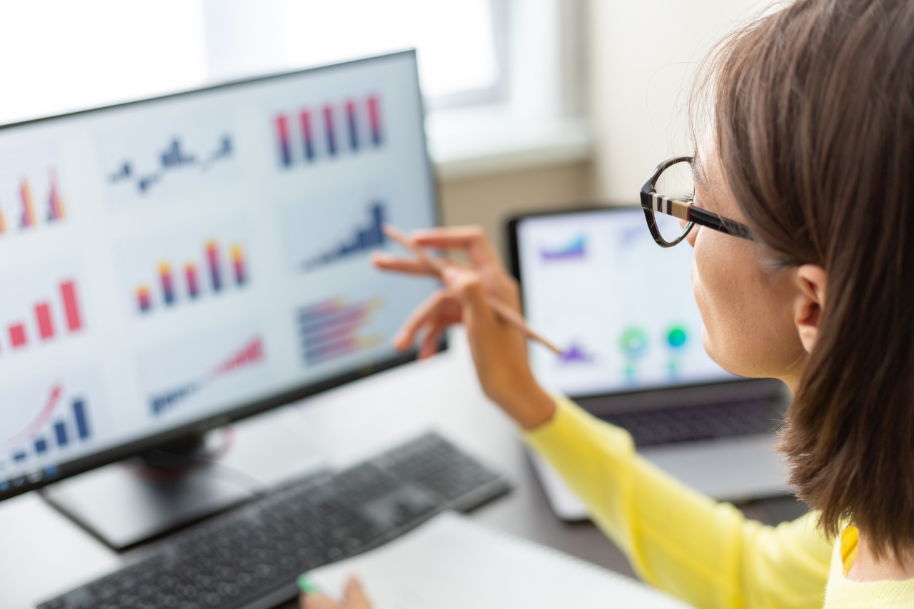 Woman looking at computer with graphs displayed