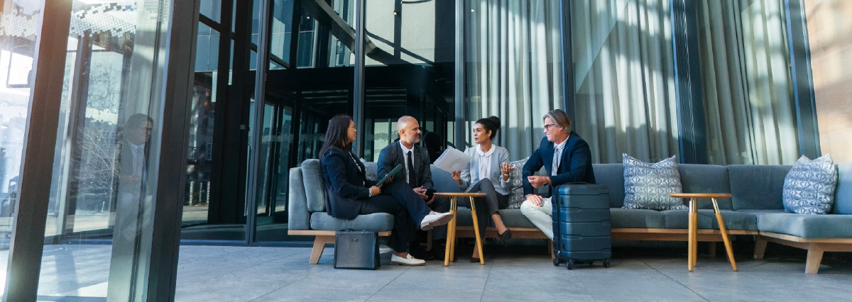 Business travel, meeting and people on couch in airport, terminal lounge and lobby with professional employees. Entrepreneurs, luggage and collaboration for b2b trip, work convention and diversity