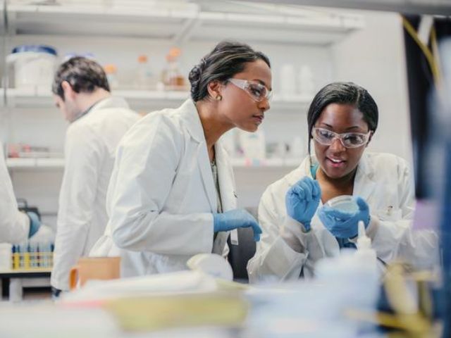 Due professioniste con camici, guanti e occhiali, all'interno di un laboratorio