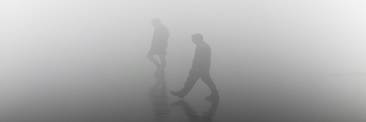 image of two people walking in fog