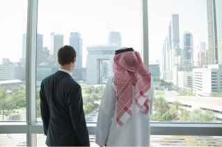 2 people in an office, looking towards the view from outside to Dubai International Financial Center 