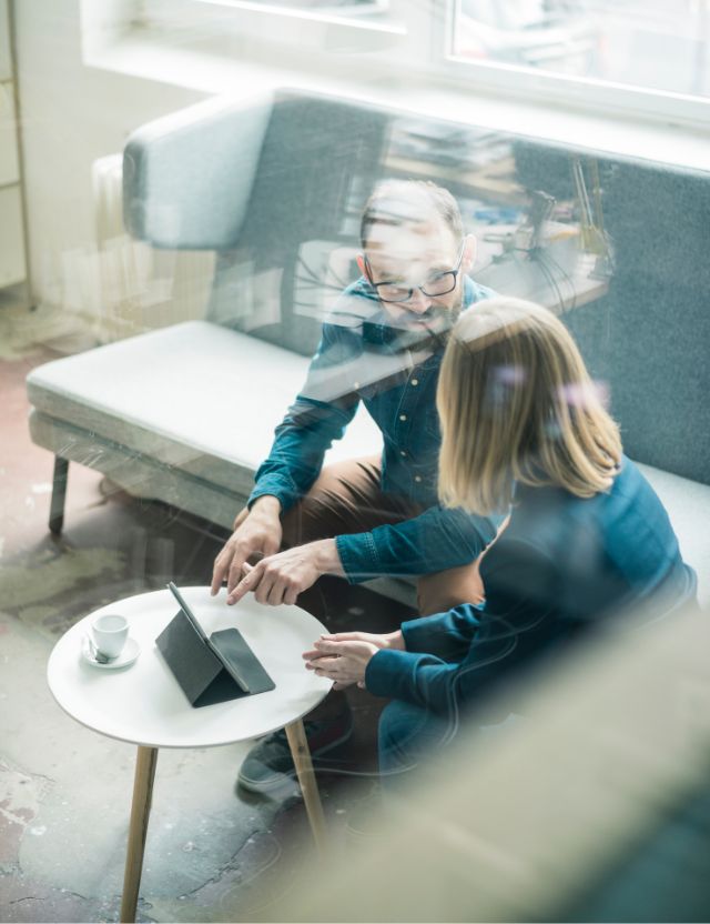 man and woman sitting and discussing business mater with tablet on the table front of them 
