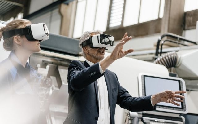 man and women in a modern factory. Both man and women are wearing virtual reality headsets 