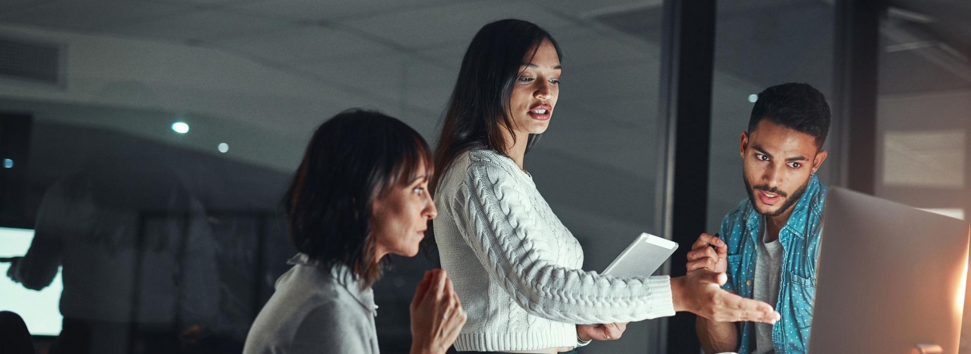 Allianz Trade products. 3 employees discusing work while looking at a desktop computer