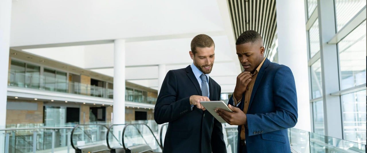 Two man talks in front of the ipad in the office