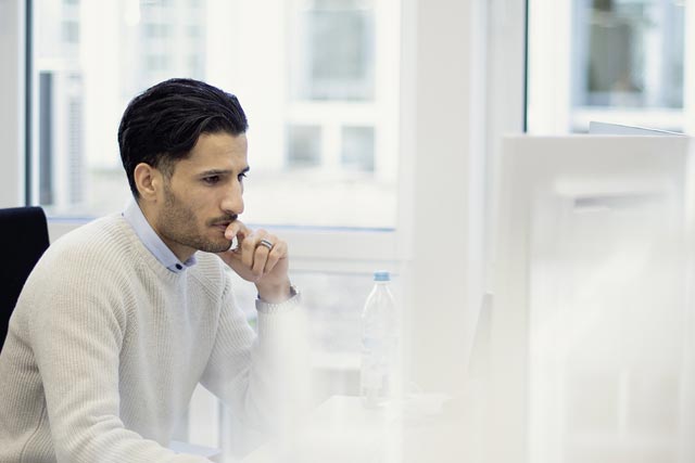 Man in fornt of laptop with the newspaper