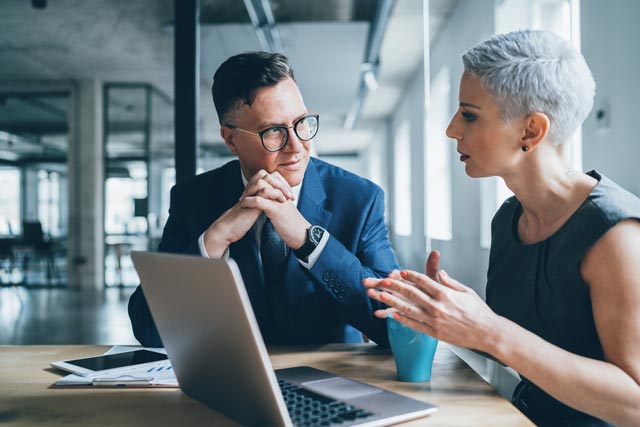 man and woman in front of the laptop in the office