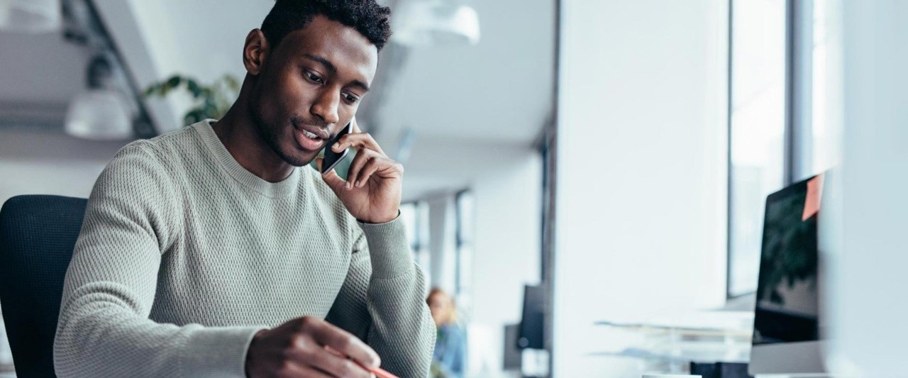 man in front of the desk talking over the phone