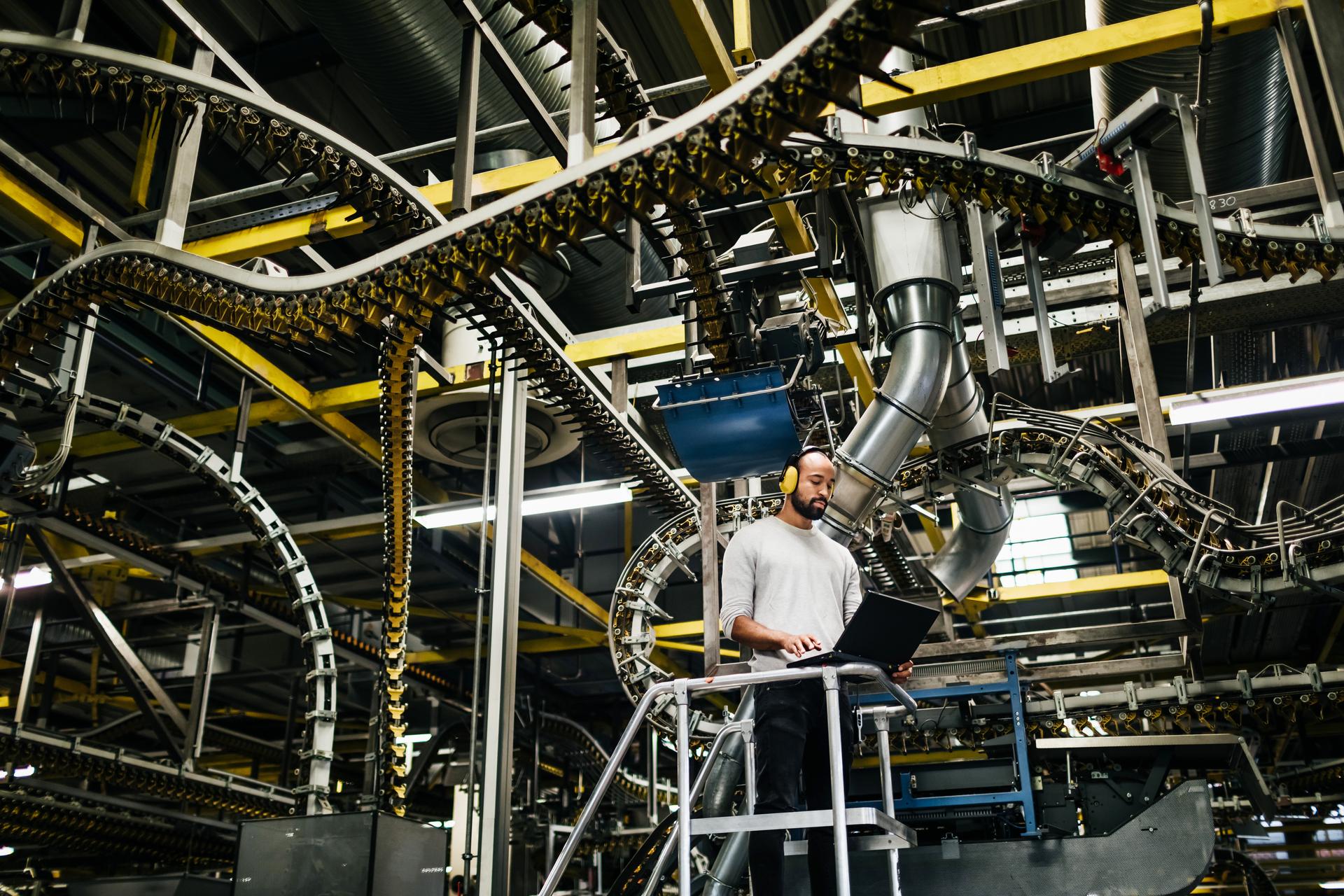 man-using-laptop-in-front-of-a-huge-machine