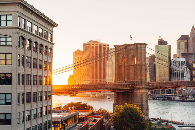 sun setting behind bridge and city skyline