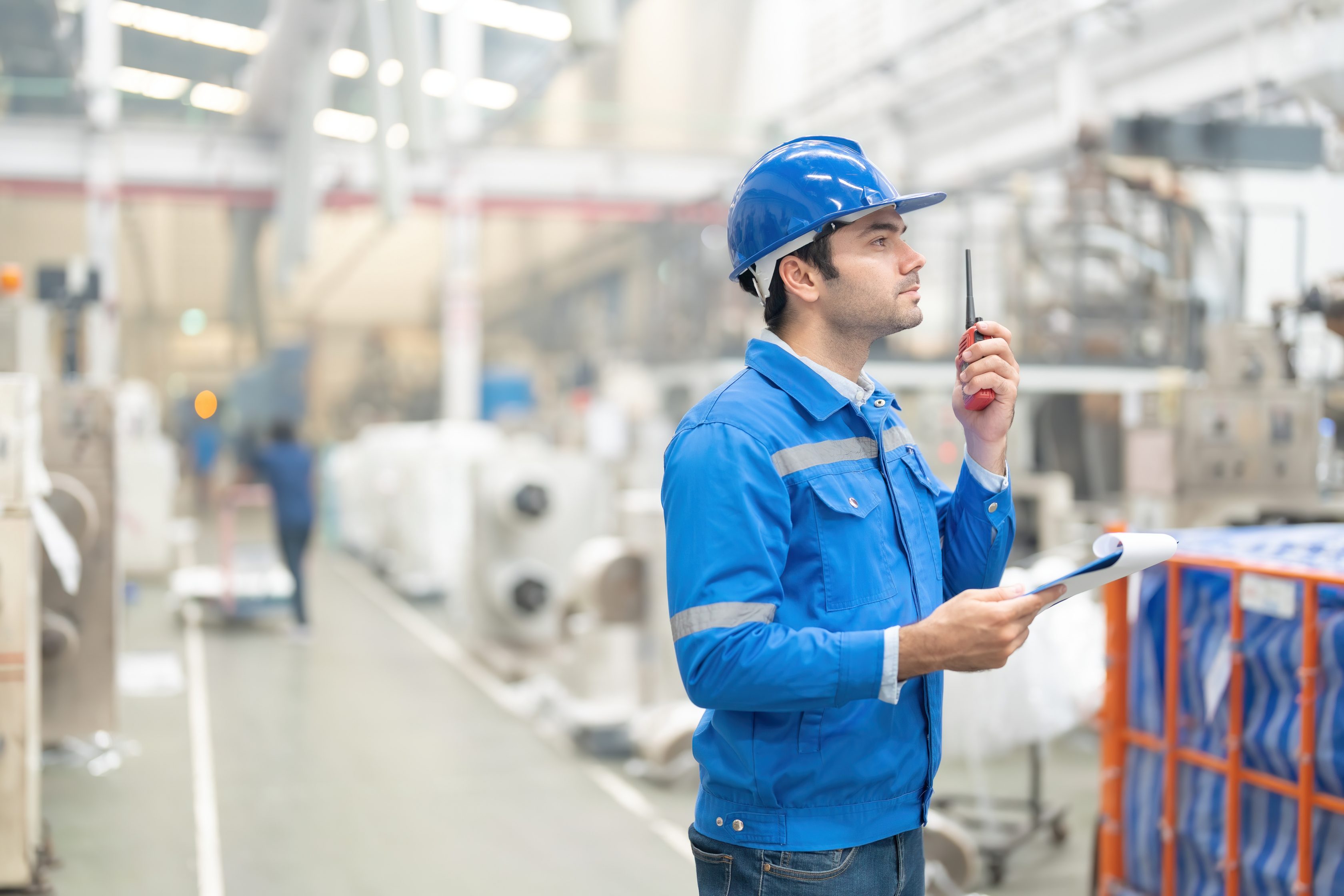 man standing in factory operating a radio device
