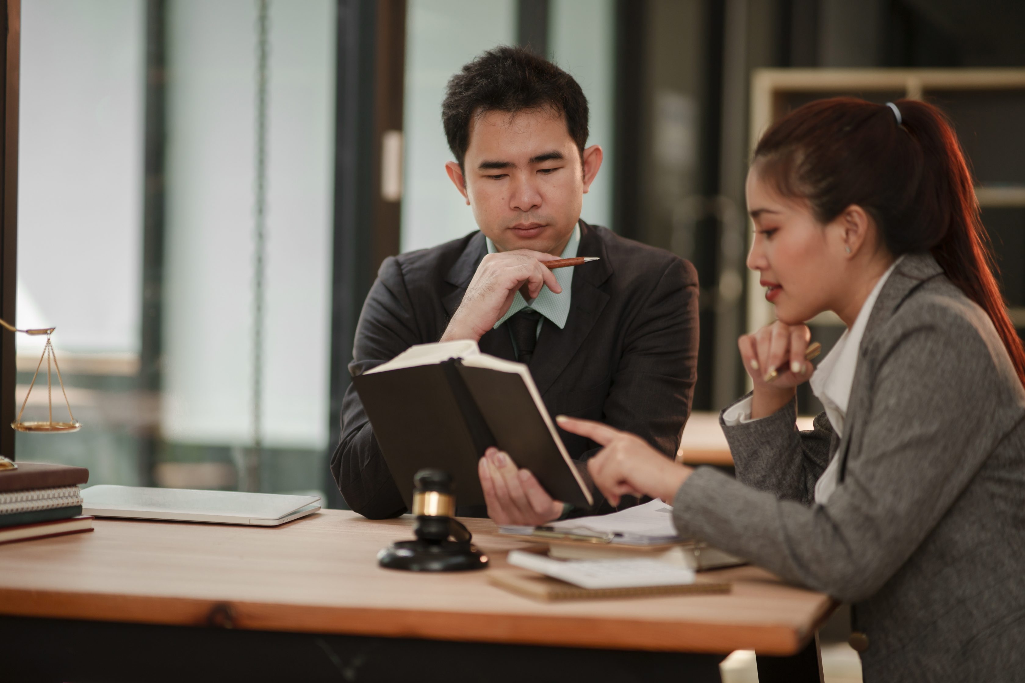 man and woman looking intently down at book together in office setting