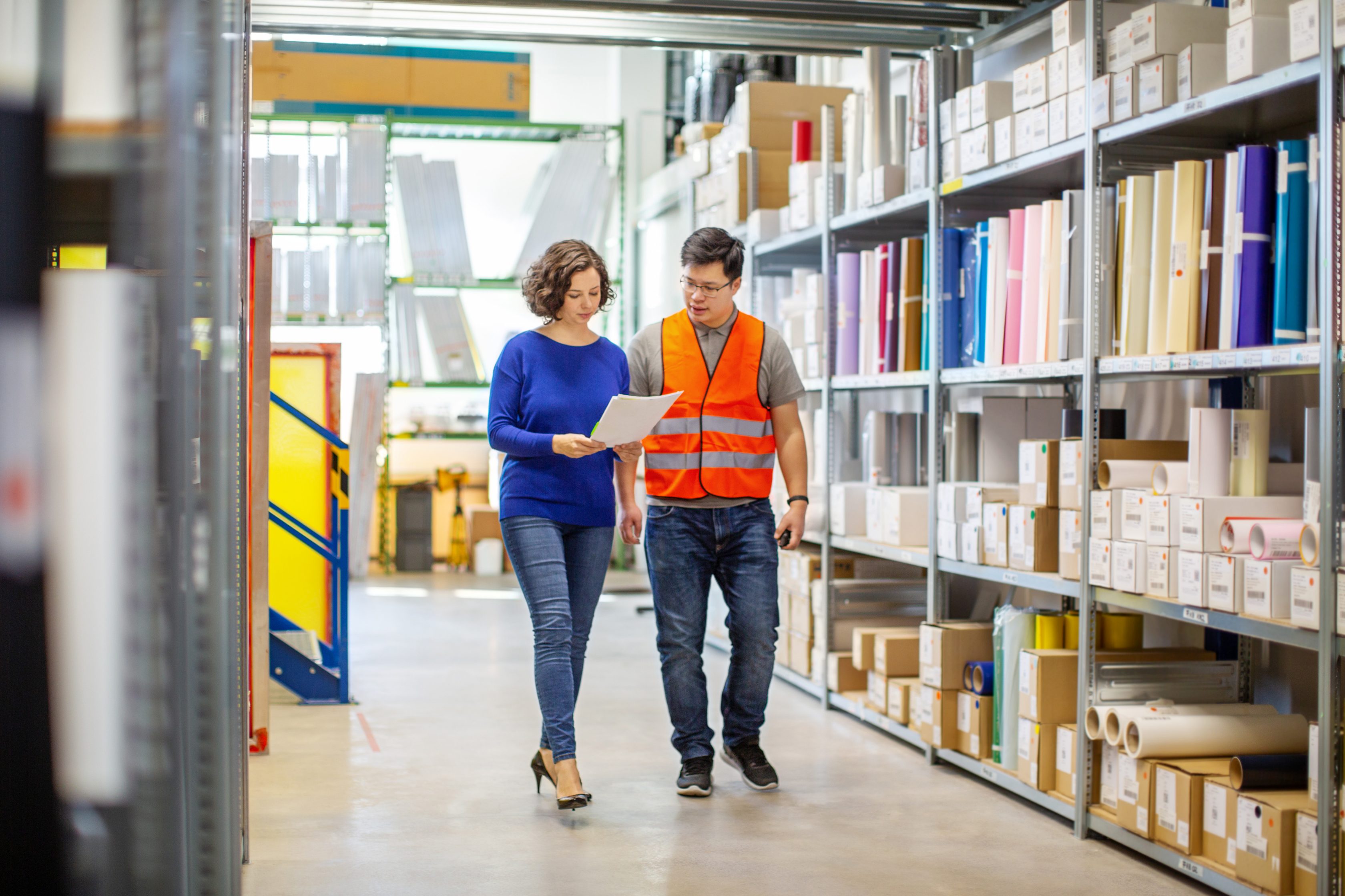 man and woman looking at paper while walking in factory