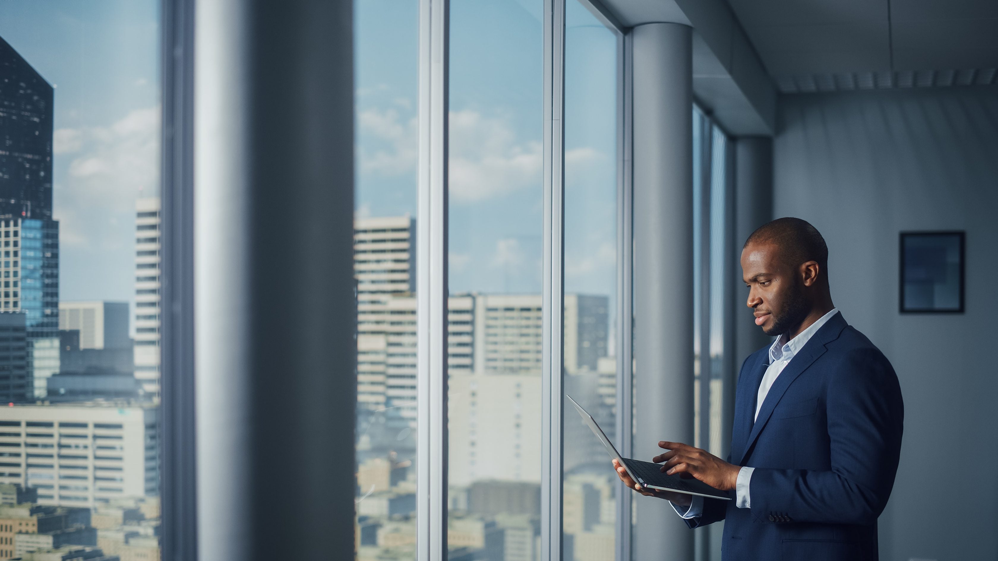 man on tablet next to glass window with city in background