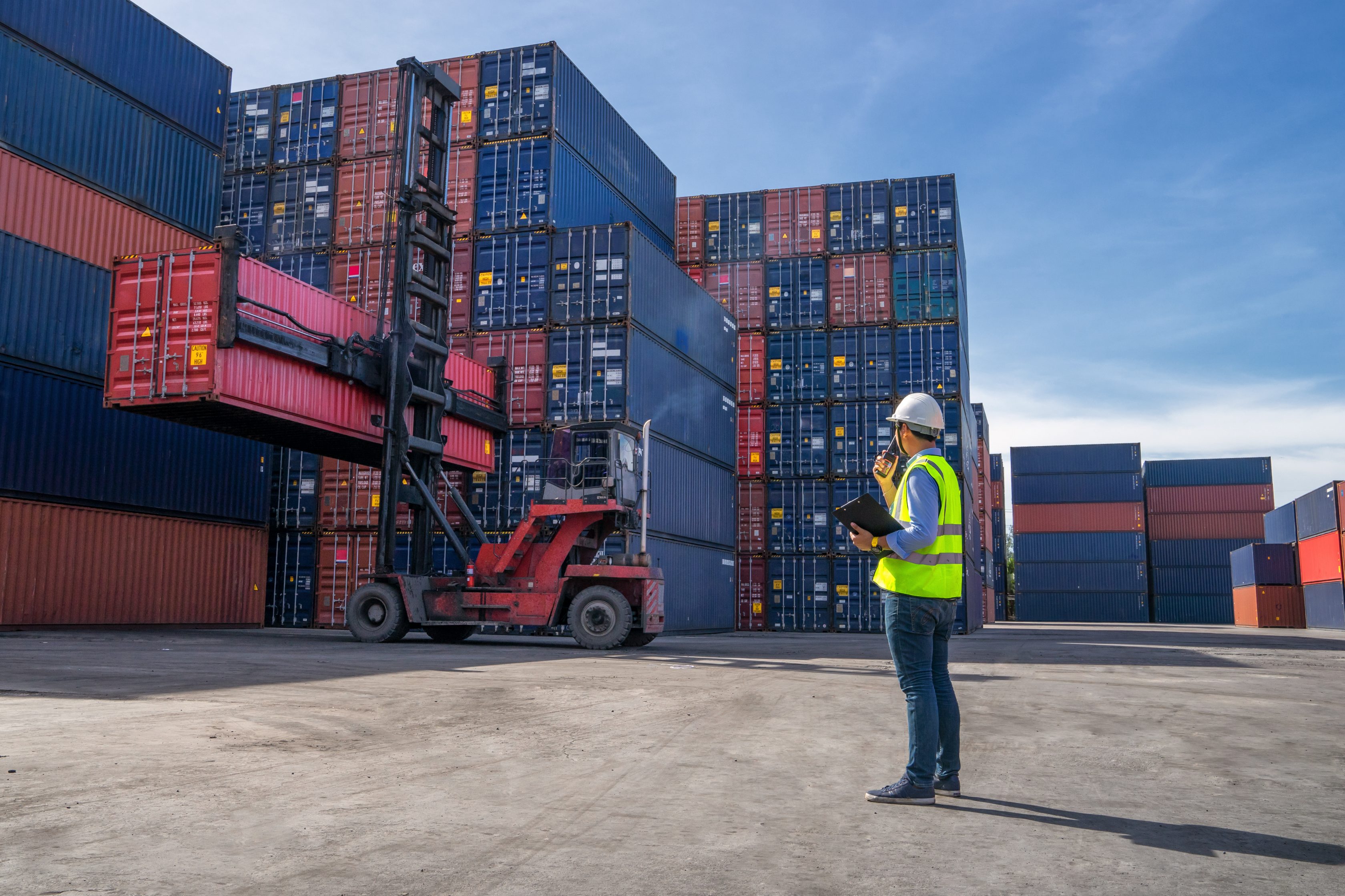 man standing in port with shipping containers in background