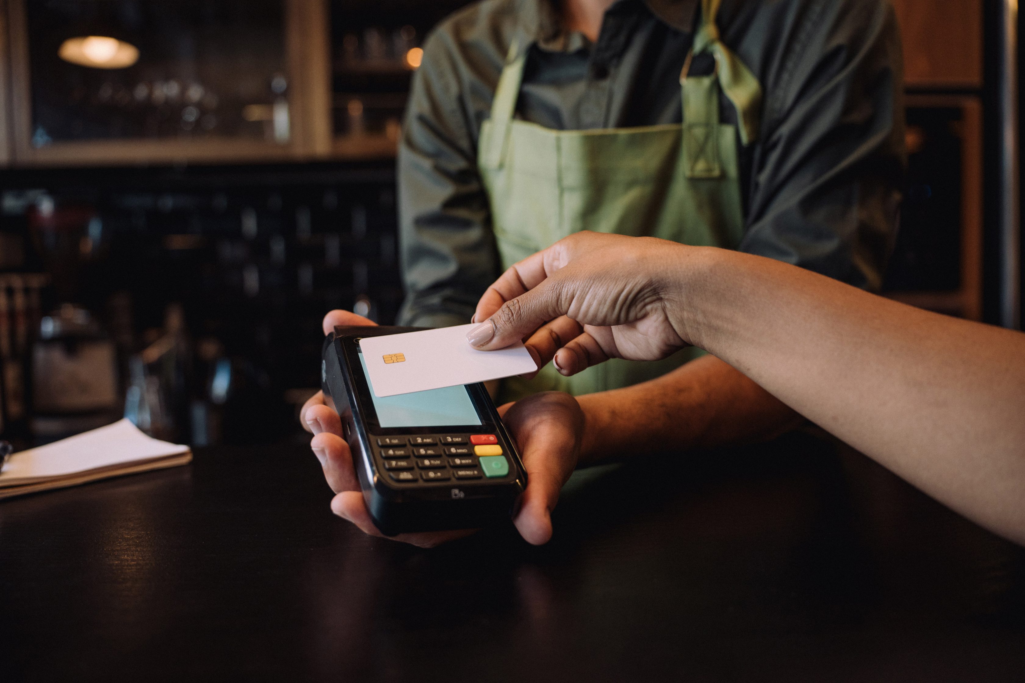 caucasian arm reaching to a POS system to tap a credit card