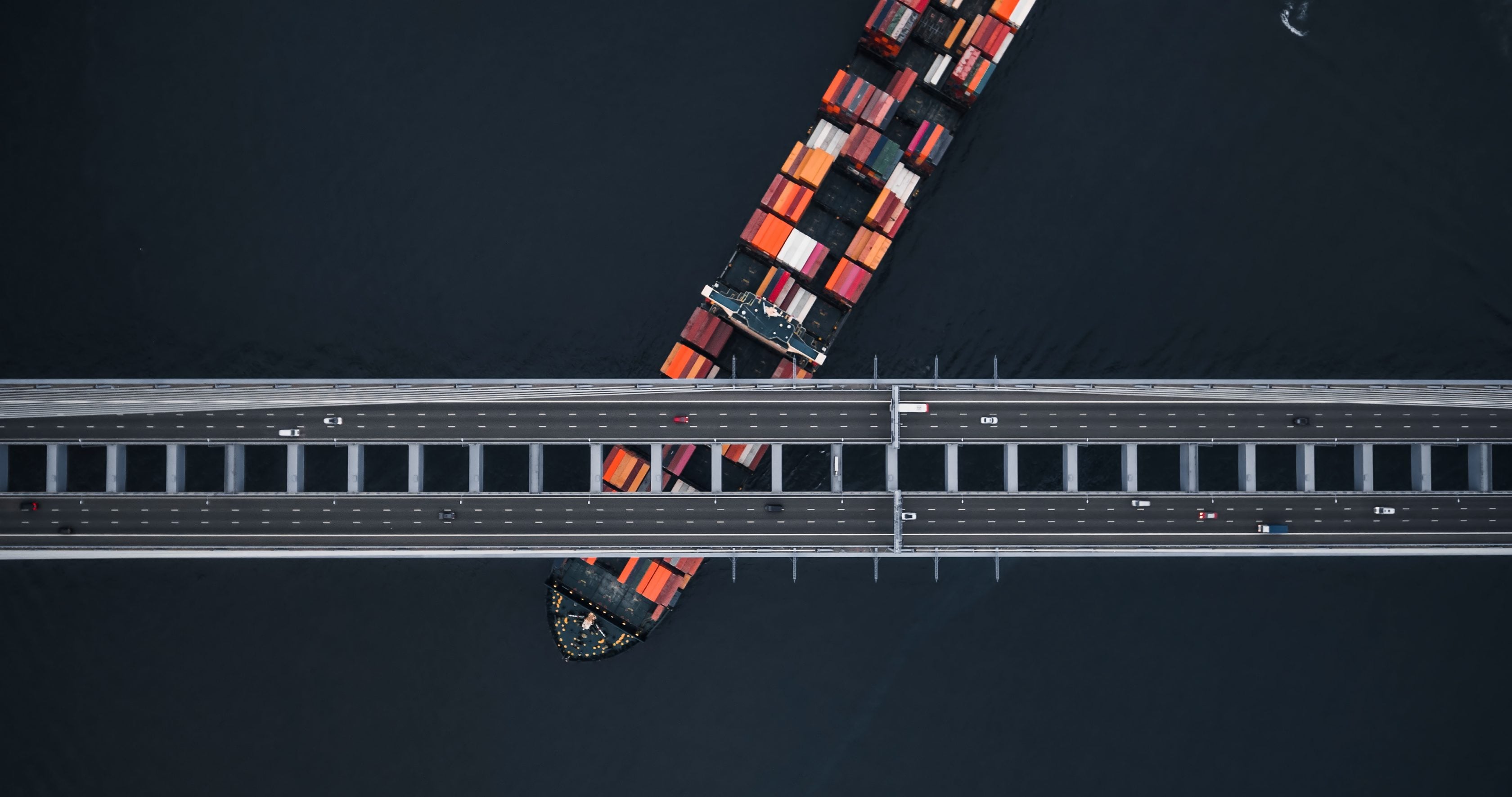 cargo vessel passing under bridge from overhear view