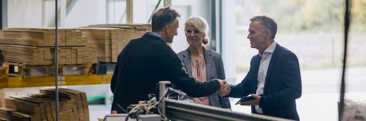 two men shaking hands with woman standing beside them