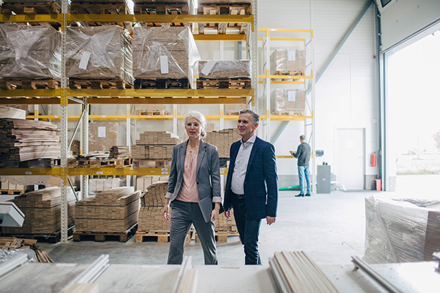 two co-workers in warehouse discussing trade credit insurance