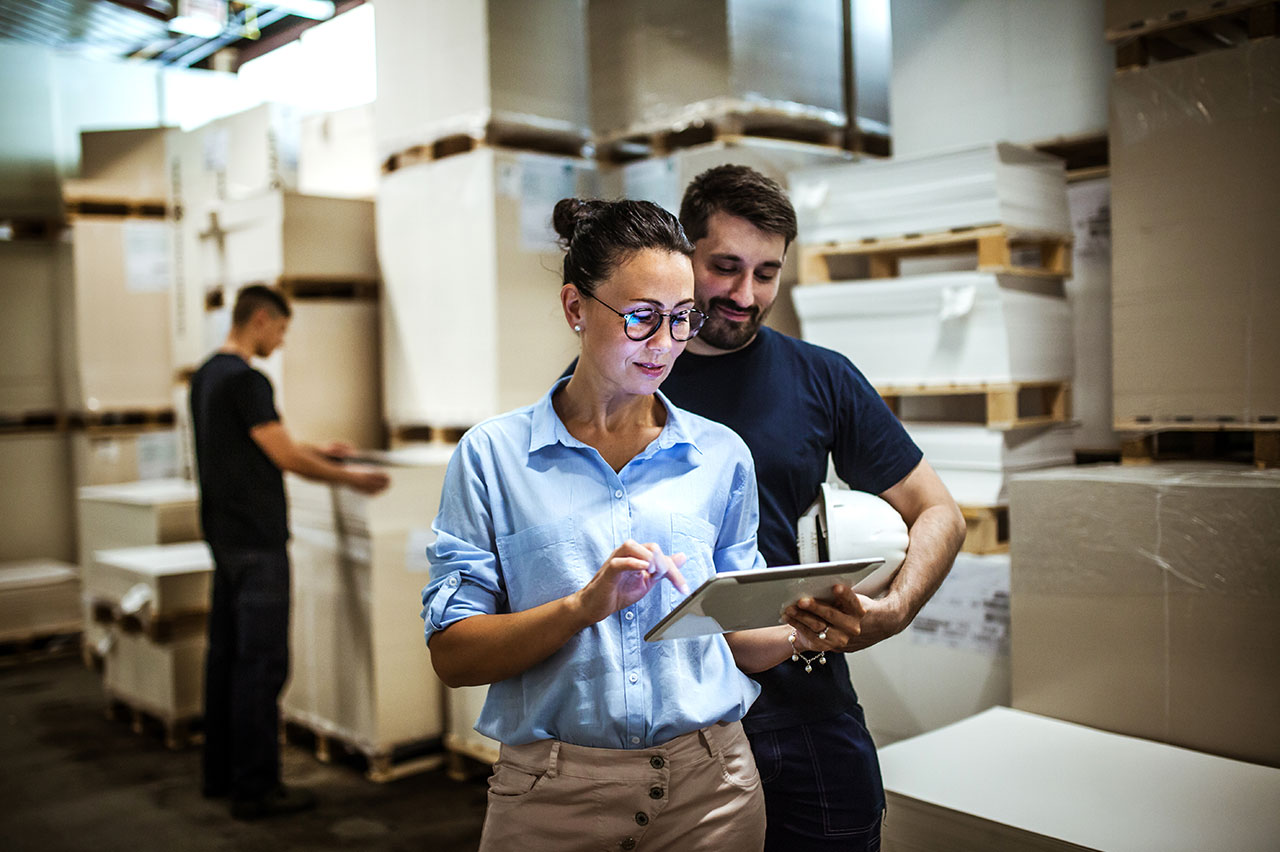 woman holding tablet and man looking over her should at tablet