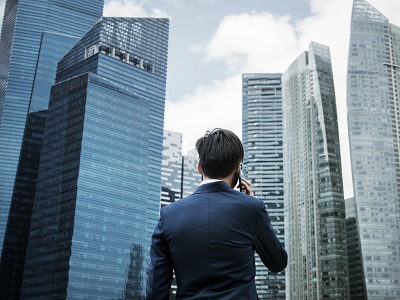 A businessman facing contemporary corporate skyscrapers in a financial district, viewed from the back