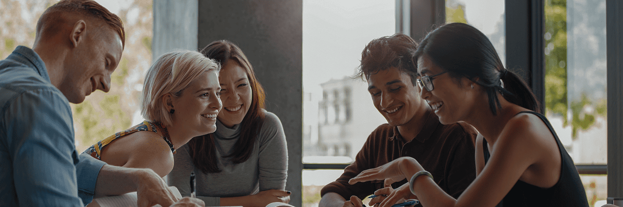 a group of colleagues talking around a table, smiling
