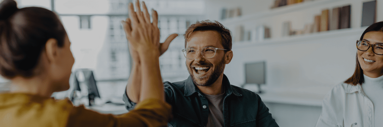 coworkers high-five, and a women watching them smiling