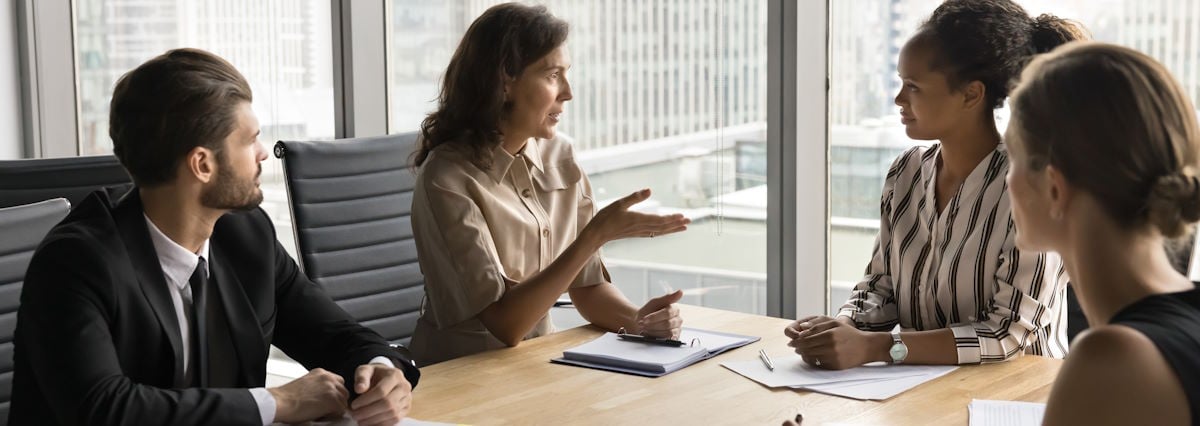 4 business people talking in a glass office