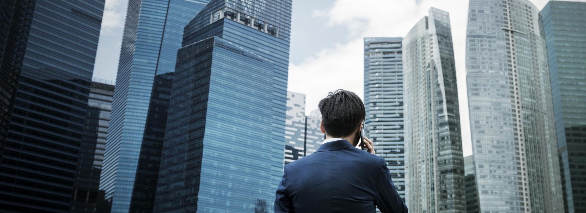 Un homme d'affaires faisant face à des gratte-ciel d'entreprise contemporains dans un quartier financier