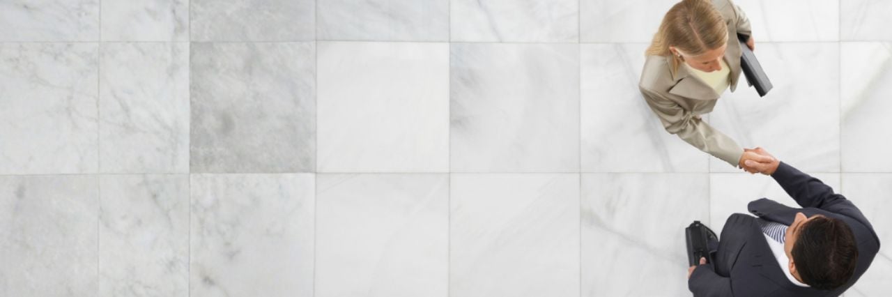 Top view of a businessman and woman shaking hands in office lobby