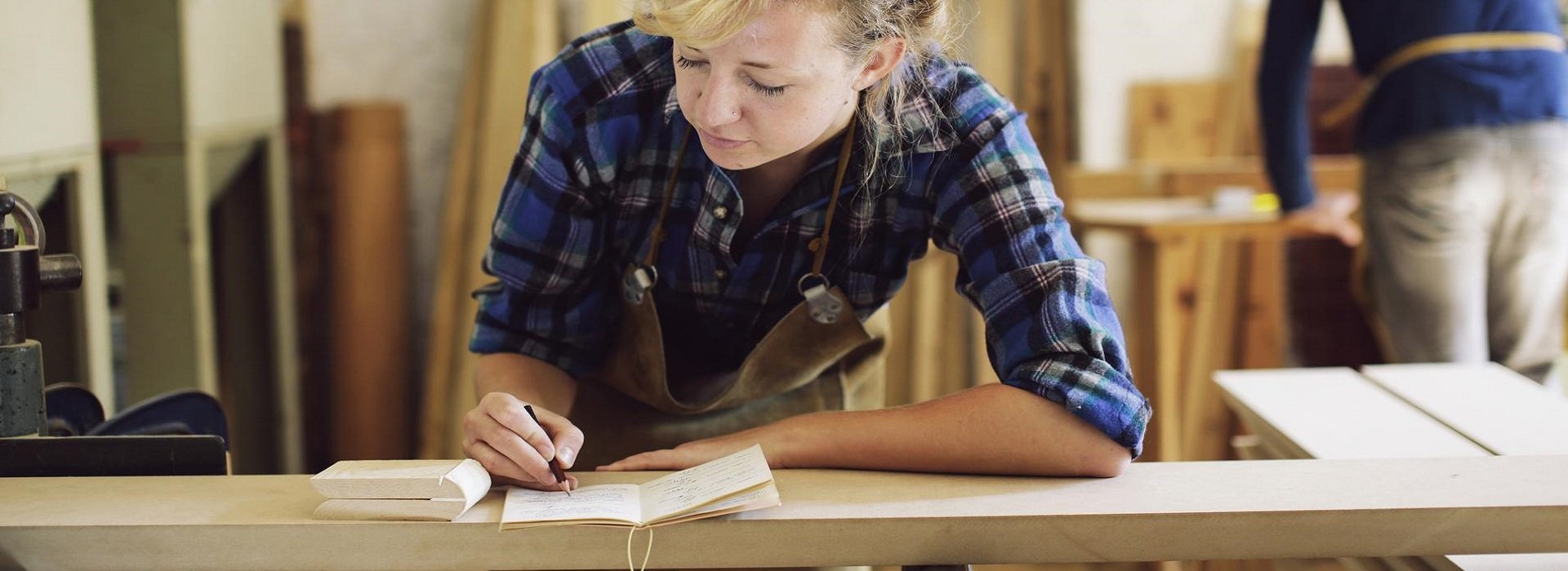 Artigiana del legno annota delle misure nel suo laboratorio