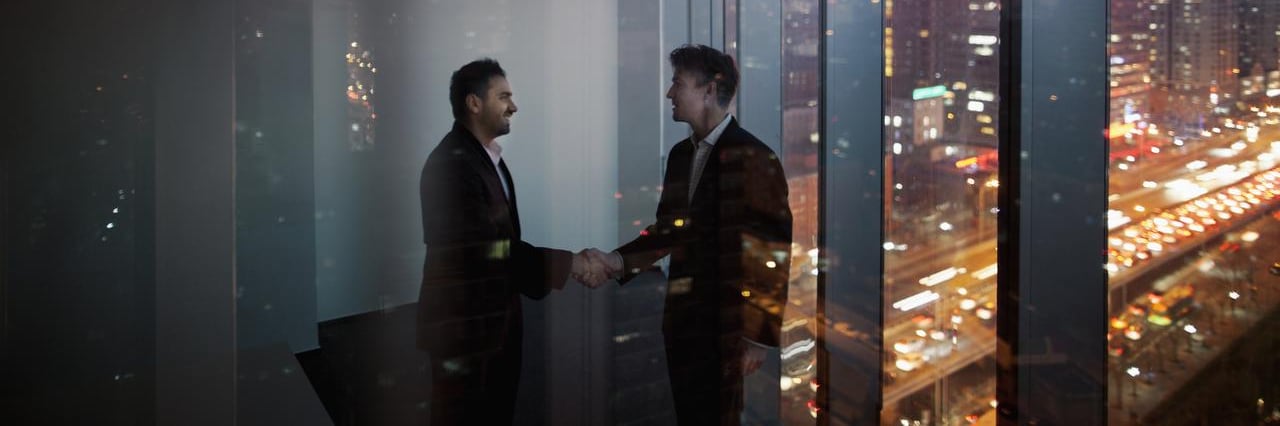 Un imprenditore e un cliente si stringono la mano in un ufficio con vista sulla città