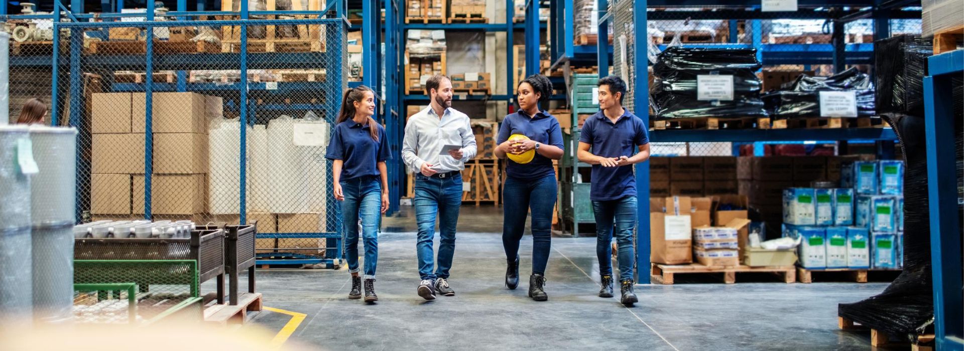 Tre operai e un manager camminano all'interno di un magazzino