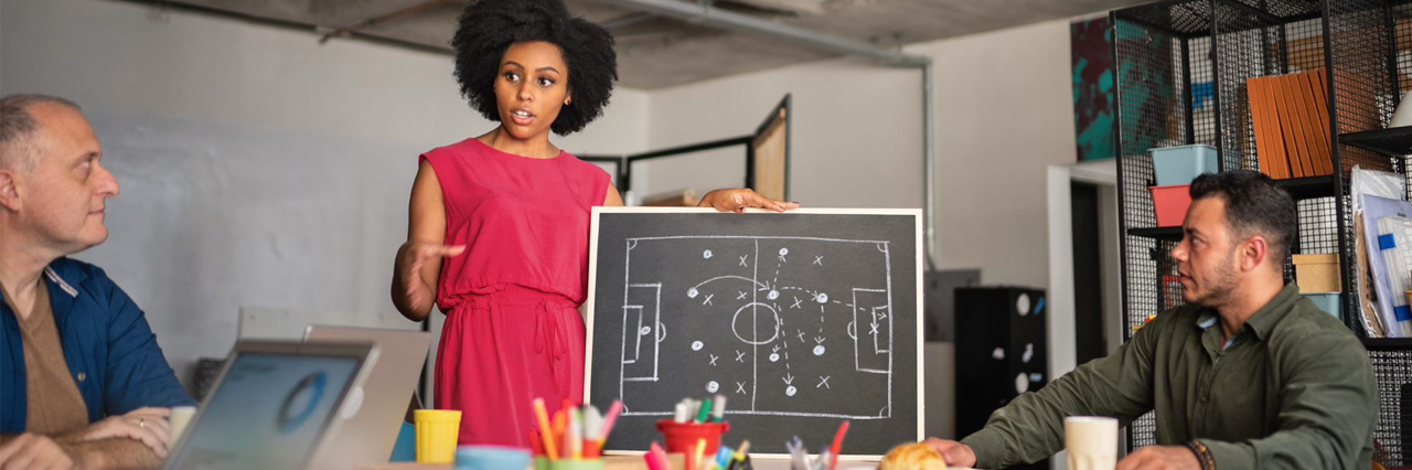 Un'allenatrice mostra uno schema di gioco su una lavagna