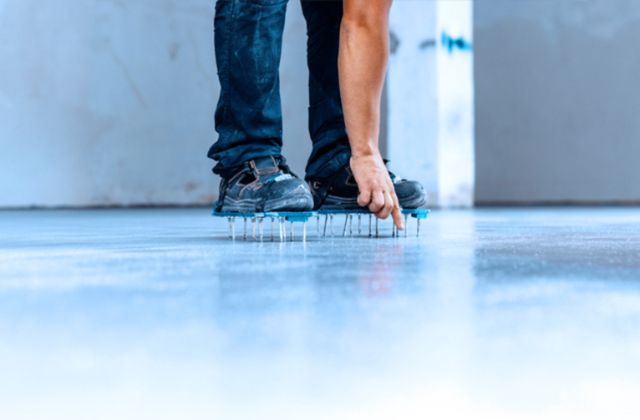 Un operaio edile lavora su una superficie, indossando scarpe chiodate per una maggiore aderenza e stabilità