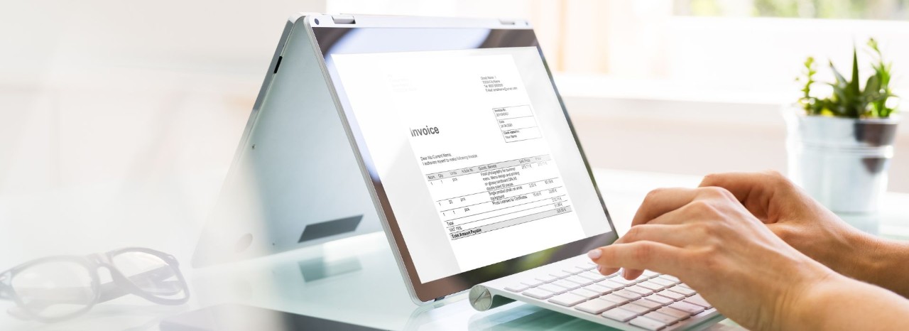 Un'impiegata nel suo ufficio compila una fattura al computer