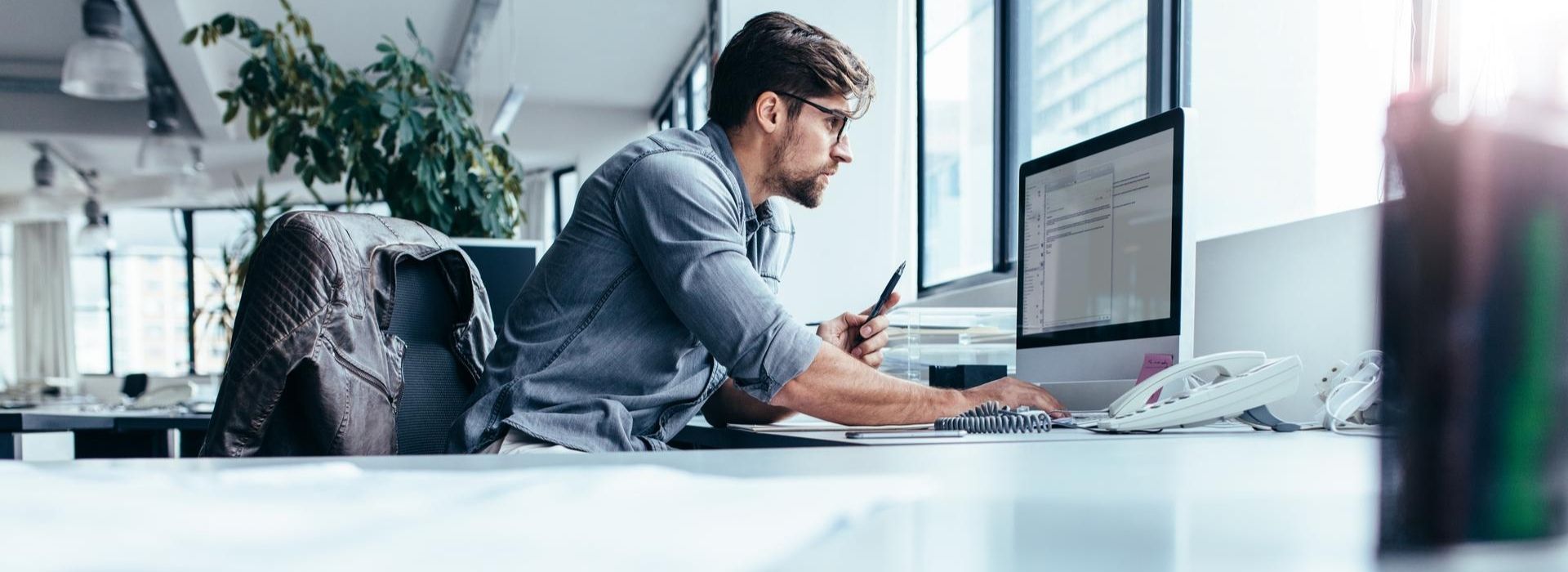 Uomo lavora al computer seduto alla sua scrivania in ufficio