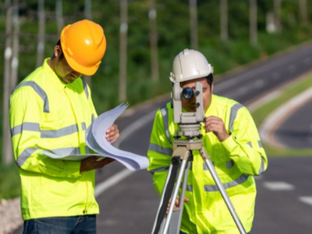 Due ingegneri topografi con attrezzatura su un cantiere stradale.