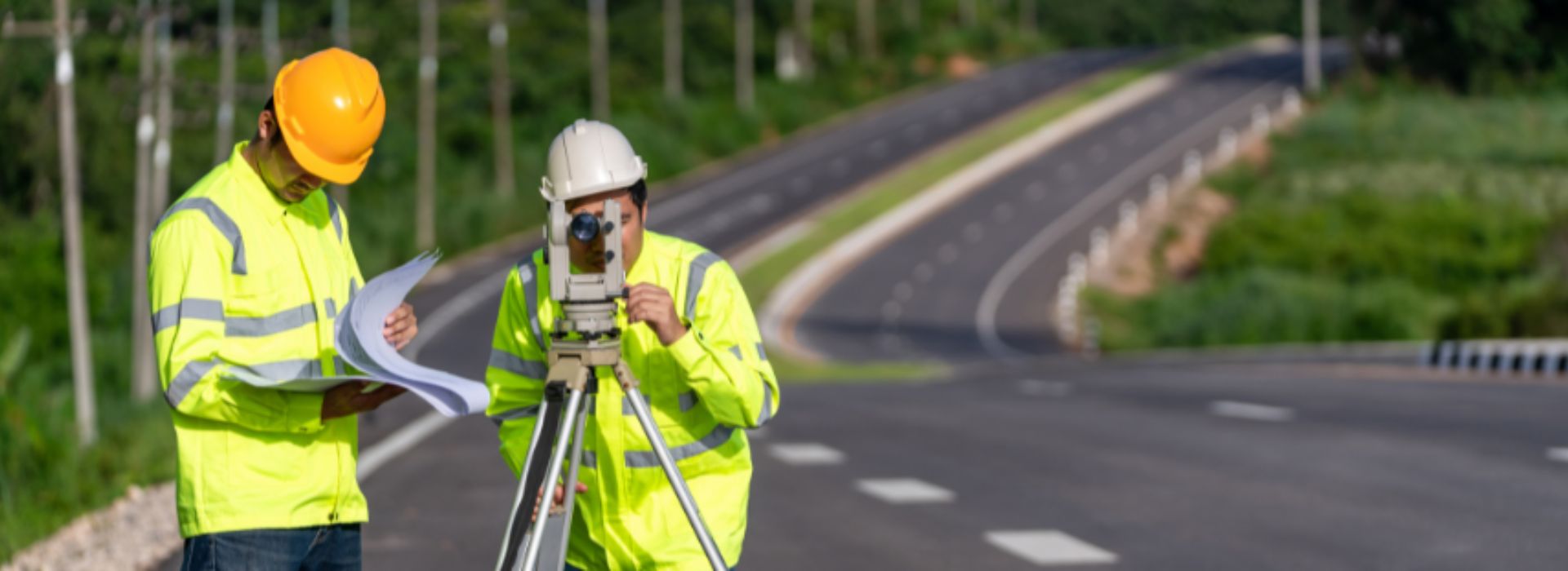 Due ingegneri topografi con attrezzatura su un cantiere stradale.