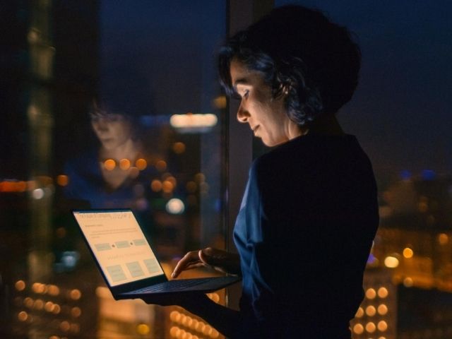 Imprenditrice in ufficio, di sera, lavora al computer