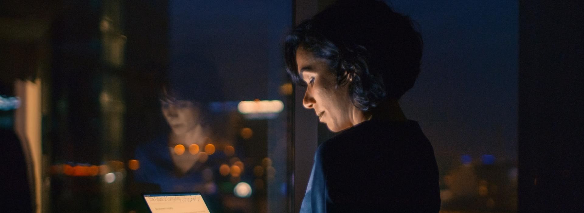 Un'imprenditrice in ufficio, di sera, lavora al computer